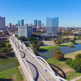 A view of the Seventh Street bridge leading into downtown Fort Worth, Texas, against a cloudless blue sky 